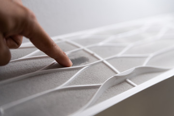 Soft focus of man hand touching the very dirty air conditioner filter with a lot of dust.