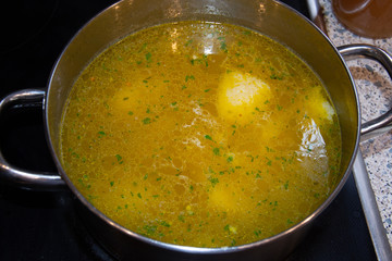 A pot of homemade chicken soup is cooking on the stove