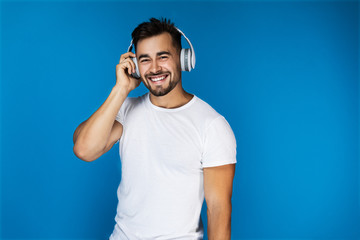 Cute european man smiles and listens something in the headphones