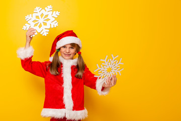 Child in Santa costume holding cardboard snowflakes