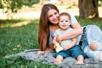 Mother with little son spend time together in green park.