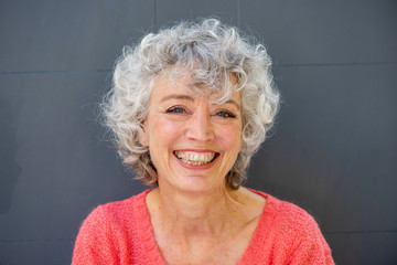Close up smiling older woman against gray background