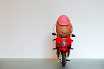 An egg riding a motorbike wearing a helmet as a symbol for road safety