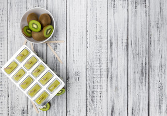 Some fresh Kiwi Popsicles on wooden background (selective focus; close-up shot)