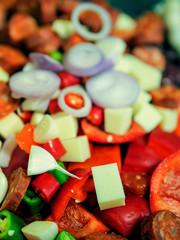 Mexican style dish with onion, cheese, garlic, beans, chorizo, red chilly peppers. Preparation stage, close up.