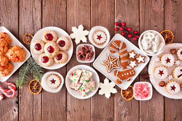 Christmas table scene of mixed sweets and cookies. Above view over a rustic wood background. Holiday baking concept.