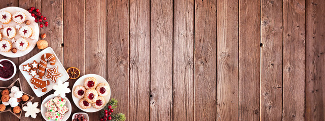 Christmas corner border banner of assorted sweets and cookies. Overhead view with a rustic wood background. Holiday baking concept.
