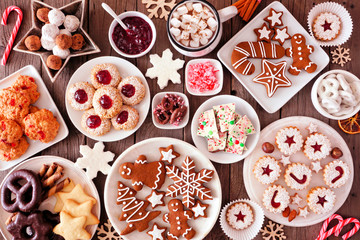 Christmas table scene of assorted sweets and cookies. Top view over a rustic wood background....