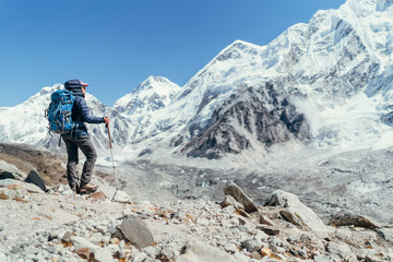 Naklejka premium Young hiker backpacker female taking brake in hike walking enjoying Khumbu Glacier. High altitude Everest Base Camp route near Gorakshep,Nepal. Nuptse 7861m on background. Active vacations concept