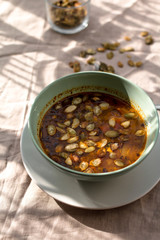 Brązowa zupa z pestkami słonecznika i dyni na lnianym obrusie