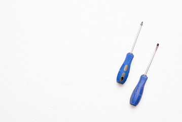 Screwdriver with blue handle on a white flat lay background with copy space.