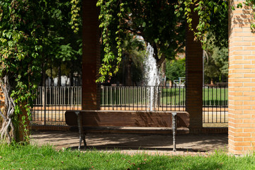 Fountain, bench and climbing plant in a beautiful green city park. Valencia, Spain