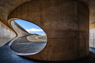 Concrete curvy arch tunnel by the highway under the cloudy sky during daytime