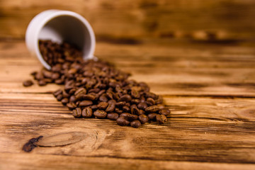 White cup and scattered coffee beans on wooden table