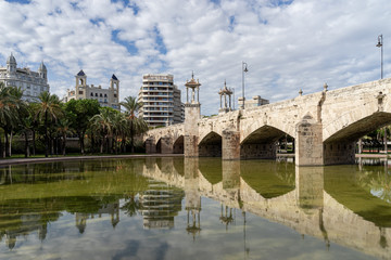 Reflections of an ancient stone bridge across old river bed. Puente del Mar, Turia river, Valencia, Spain