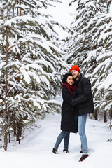 Fototapeta na wymiar Loving couple hugging in the winter forest among snowy pines
