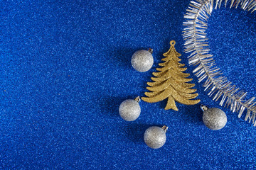 Toy Christmas tree, silver ornaments and tinsel on a blue shiny background. Flat lay. Happy New Year and Merry Christmas - Powered by Adobe