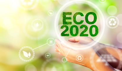 A woman's hands holding a text ECO 2020. Environmental biodiversity in ecosystem concept. Backdrop as a concept of energy efficiency. The power of green energy. Concept of renewable energies