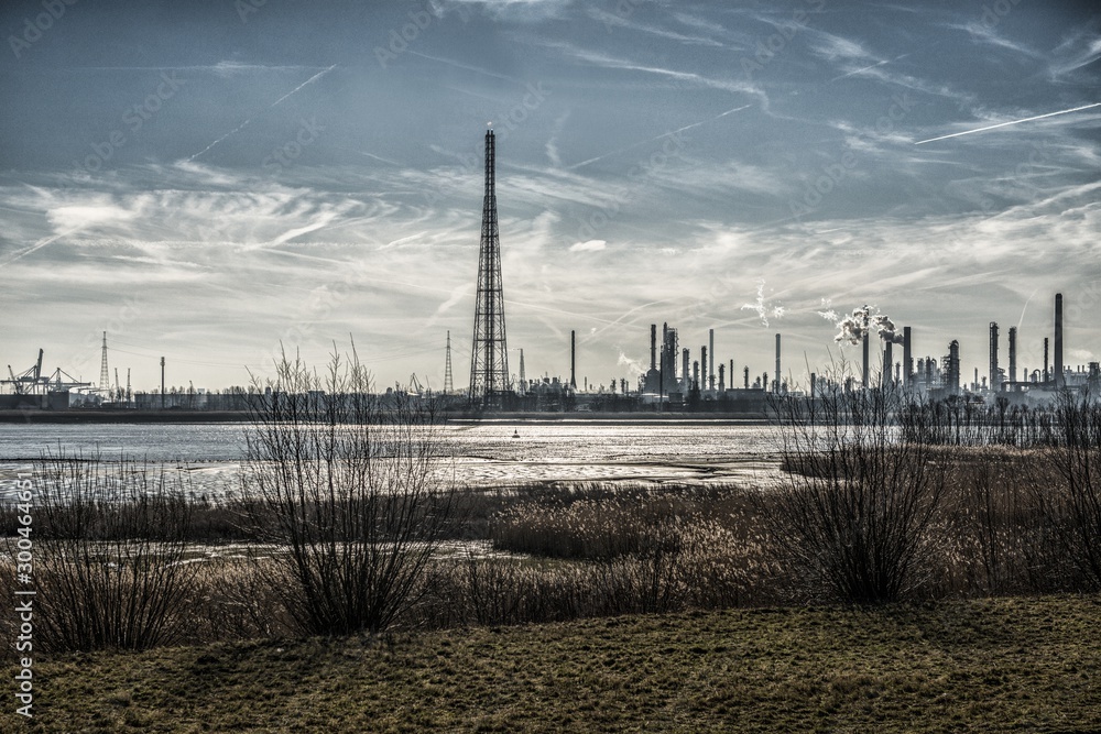 Sticker industrial buildings on the shore surrounded by grass under sky