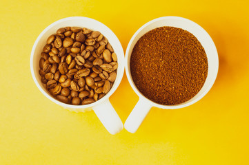Coffee beans and ground coffee in cups on yellow background