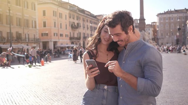 A couple looking at their pictures on the phone in square Italy