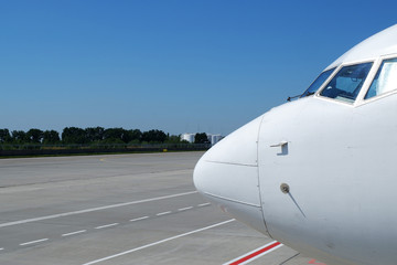 Obraz premium Airplane nose details against clear blue sky. View of jumbo-jet airliner front and nose in generic, white paint scheme.