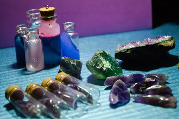 bottles with gemstone and magical liquid, amethyst geode and fluorite on colorful background