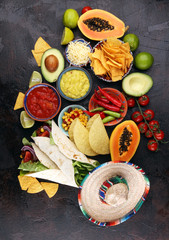 Mexican food, including tacos, guacamole, nachos and pepper on rustic table