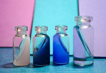 Four tiny bottles with magical liquid on colorful background