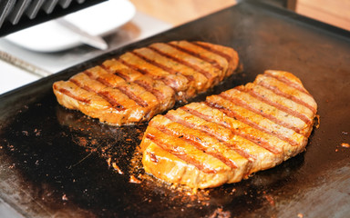 Two pork steaks grilled on electric grill, metal plate