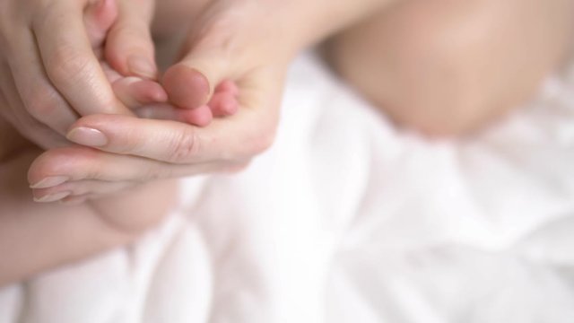 female hands massage the baby in bed. close-up