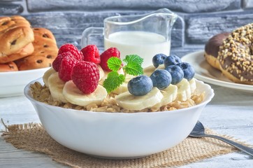 Delicious sweet healthy breakfast. Oatmeal with bananas, blueberries and raspberries.