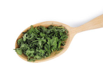 Wooden spoon with dried parsley on white background, top view