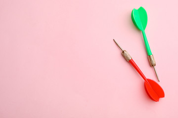 Plastic dart arrows on pink background, flat lay with space for text