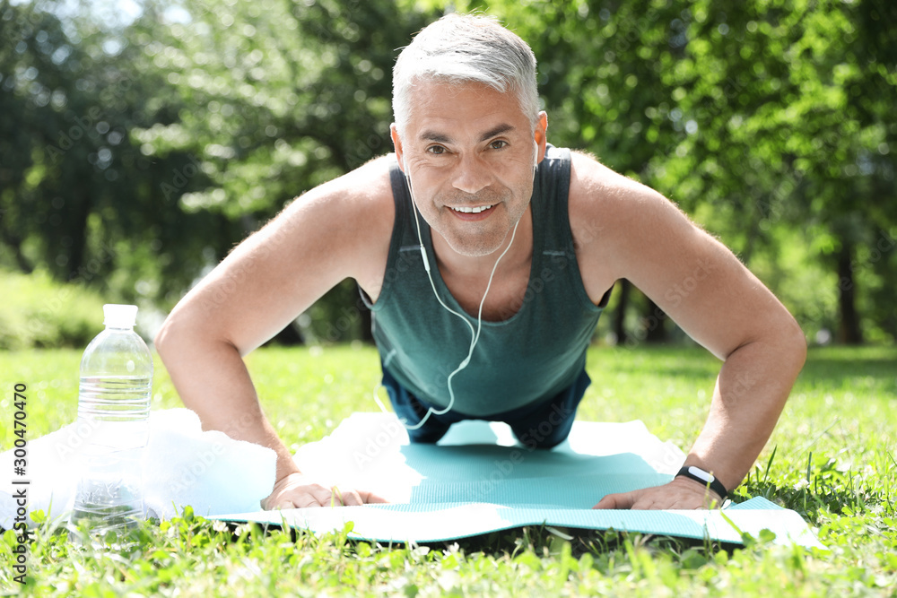 Wall mural handsome mature man doing exercise in park. healthy lifestyle