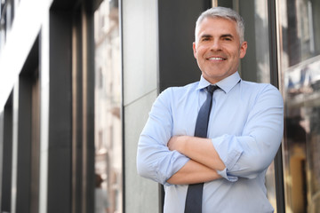 Portrait of handsome businessman in city, space for text