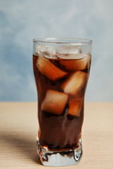 Glass of refreshing soda drink on wooden table against blue background