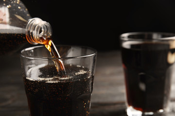 Pouring refreshing soda drink into glass on table, closeup. Space for text
