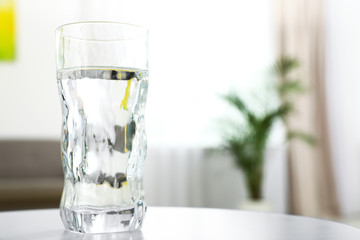 Glass of water on table in room, space for text. Refreshing drink