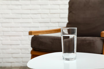 Glass of water on table in room, space for text. Refreshing drink