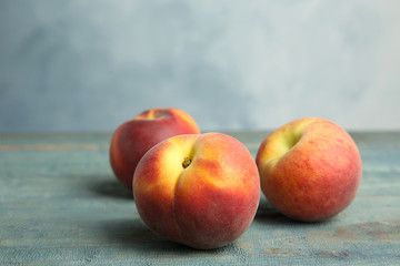 Fresh juicy peaches on wooden table against blue background, space for text