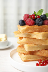 Delicious waffles with fresh berries served on white wooden table indoors