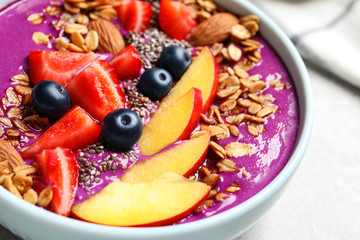Delicious acai smoothie with granola and berries in bowl on table, closeup