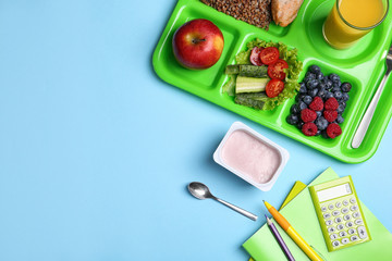 Serving tray of healthy food and stationery on light blue table, flat lay with space for text....
