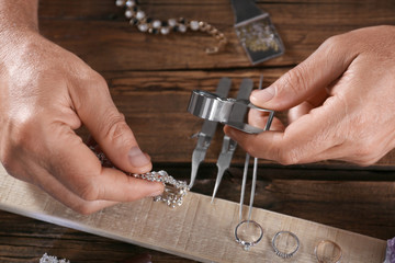 Male jeweler evaluating diamond bracelet in workshop, closeup view