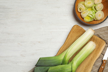 Flat lay composition with fresh raw leeks on white wooden table, space for text. Ripe onion