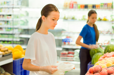 Naklejka premium Teen girls shopping in supermarket reading product information. Choosing daily product.Concept of healthy food, bio, vegetarian, diet.