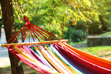 Bright comfortable hammock hanging in green garden, closeup