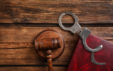 Book, handcuffs and gavel on wooden table, flat lay. Criminal law