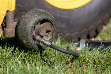 Lawnmower deck height gauge wheel bearing being lubricated with grease gun. Concept of home and...